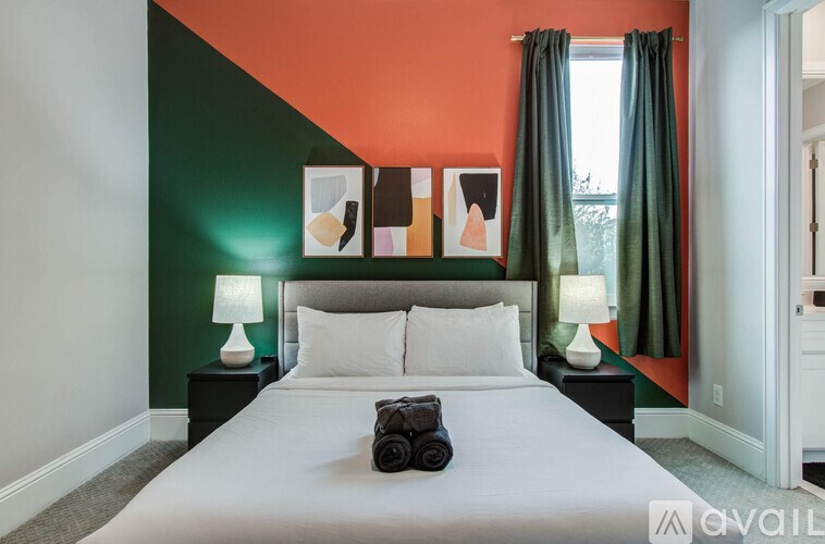 A hot tub is surrounded by a wooden fence and a patio with a couch and a fire pit.