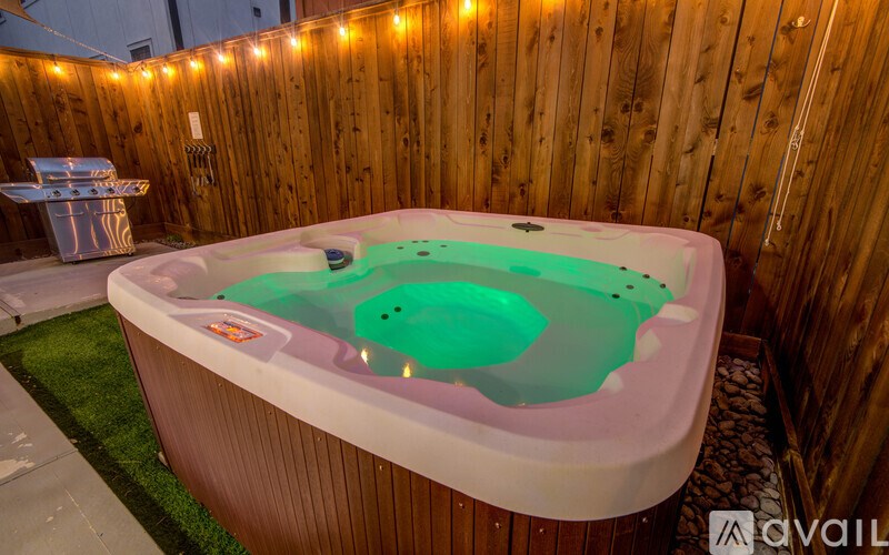 A hot tub with a green liquid inside is surrounded by a wooden wall.