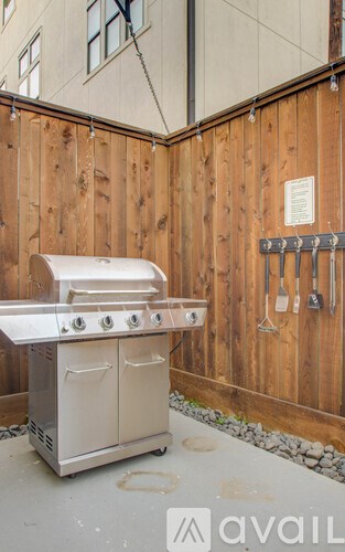 A white BBQ grill with four burners is in front of a wooden fence.