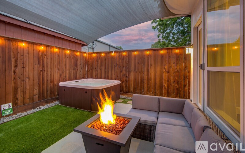 A patio with a hot tub and a fire pit.