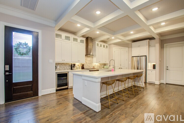 A kitchen with white cabinets and a center island with bar stools.