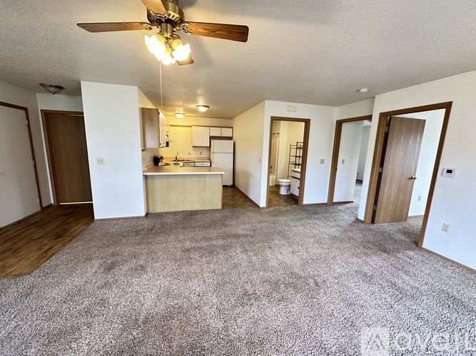 A living room with a ceiling fan and carpeted floor.