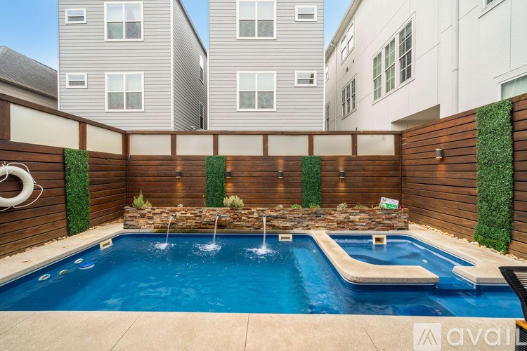 A pool surrounded by a wooden fence with a waterfall feature.