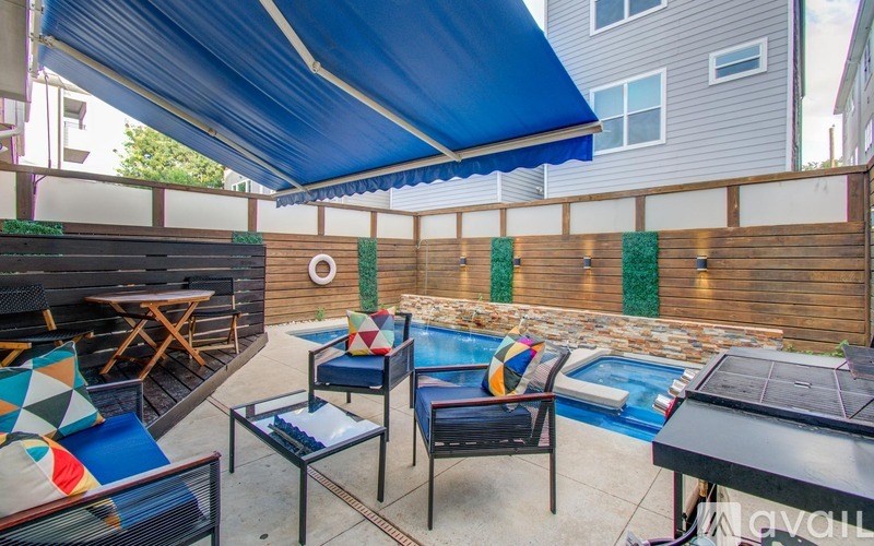 A pool area with a blue canopy and a table with chairs.