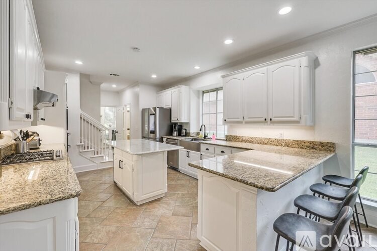A kitchen with granite countertops and white cabinets.