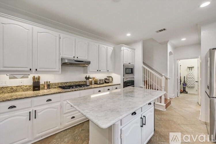 A kitchen with white cabinets and a marble countertop.