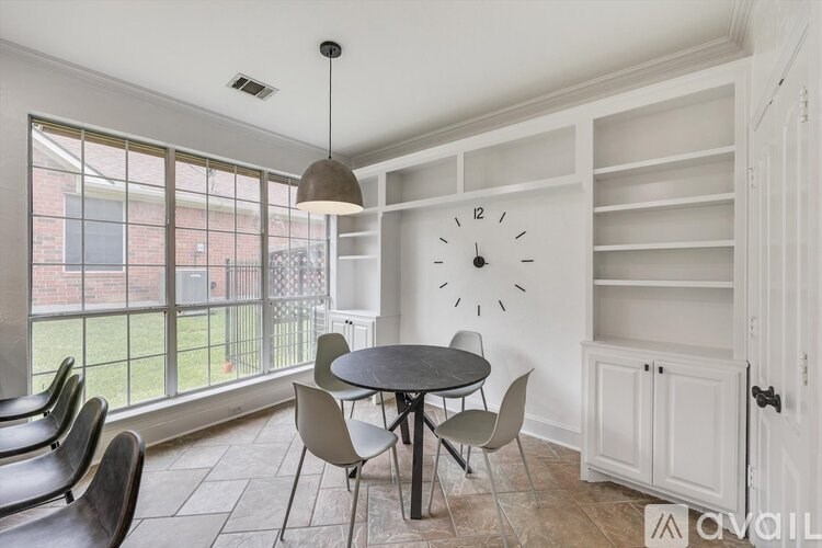 A dining room with a table and chairs and a large clock on the wall.