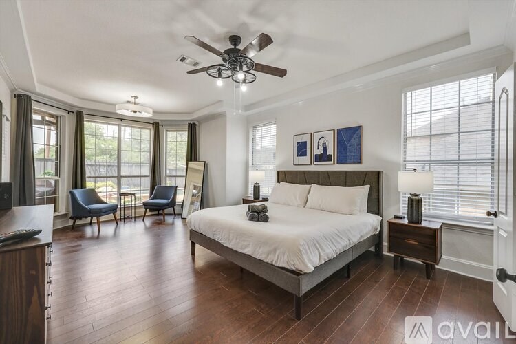 A bedroom with a large bed, a ceiling fan, and a window with blinds.