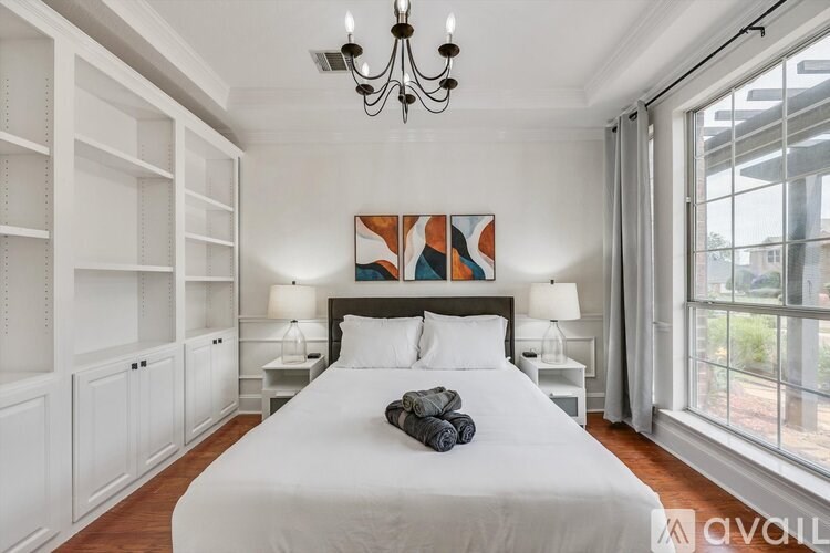A bedroom with a large bed, a chandelier, and a painting on the wall.