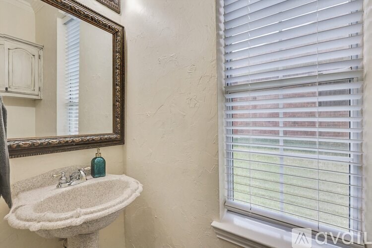 A bathroom with a sink, mirror, and window with blinds.
