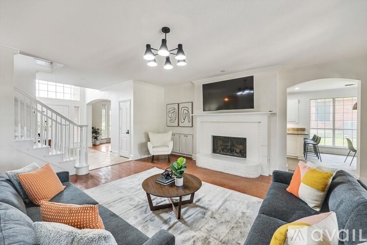 A living room with a grey couch and a white fireplace.