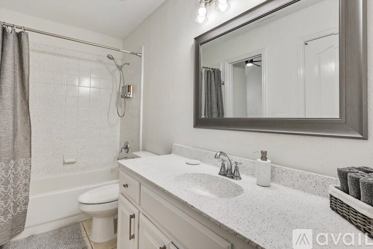 A bathroom with a white toilet, a sink, a mirror, and a shower.