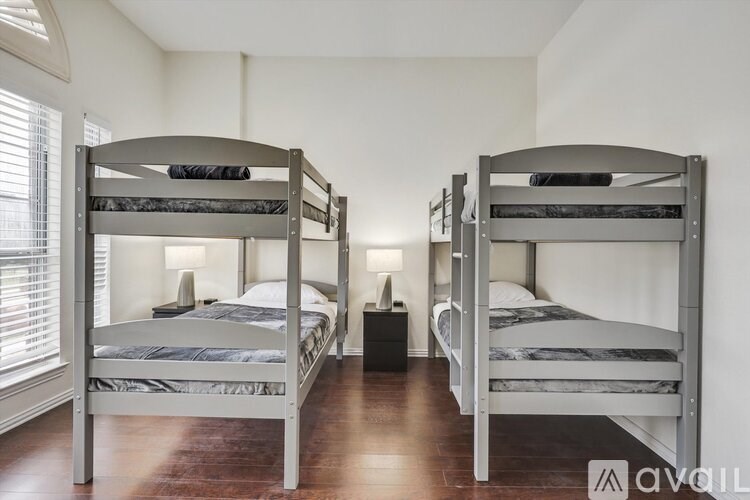 Two bunk beds in a room with wooden floors and white walls.