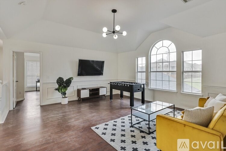 A living room with a yellow sofa and a black pool table.