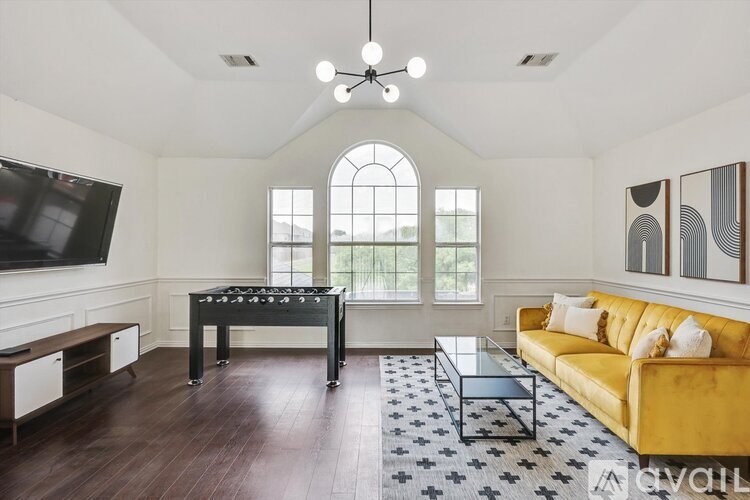 A living room with a yellow couch and a foosball table.