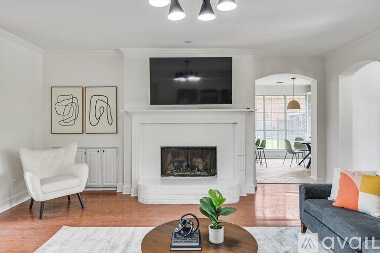 A living room with a fireplace, a chair, a plant, and a television.
