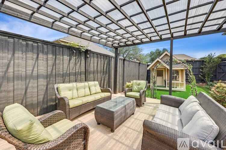 A patio with a wicker sofa and table under a white canopy.