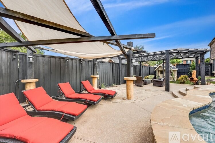 A patio with red chairs and a pool.