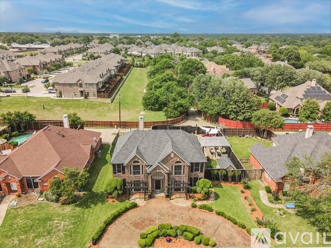 A bird's eye view of a suburban neighborhood with a large house in the foreground.