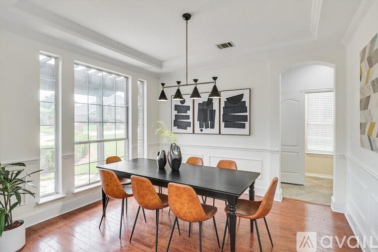 A dining room with a black table and orange chairs.