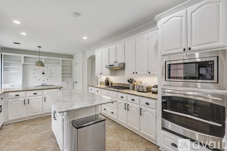 A modern kitchen with white cabinets and a marble countertop.