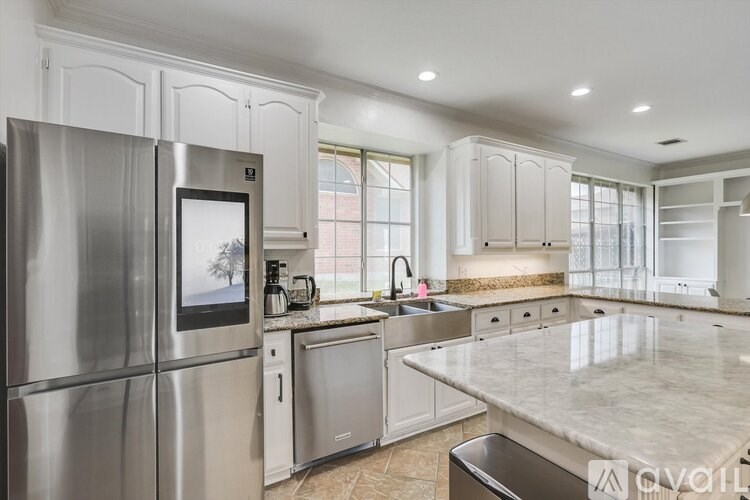 A modern kitchen with a stainless steel refrigerator and marble countertops.