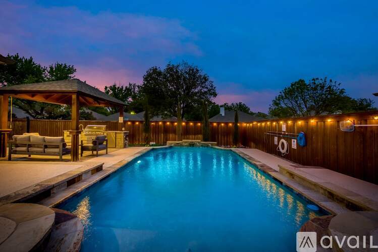 A pool with a wooden deck and a gazebo with lights around it.