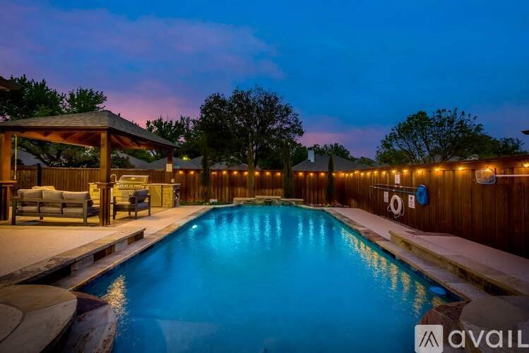 A pool with a wooden deck and a gazebo with lights around it.