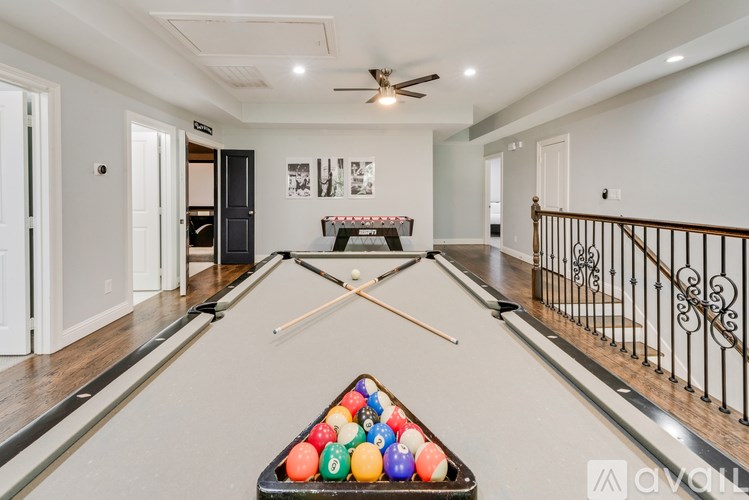 A pool table with balls and cues in a room with a balcony.