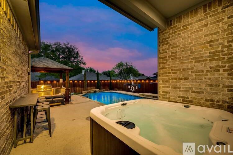 A hot tub is in the middle of a patio with a bar and chairs.