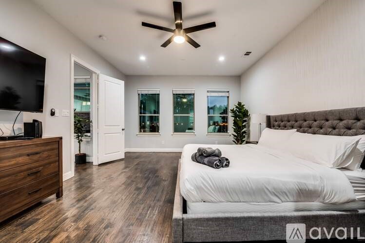 A bedroom with a large bed, a ceiling fan, and a flat-screen TV.