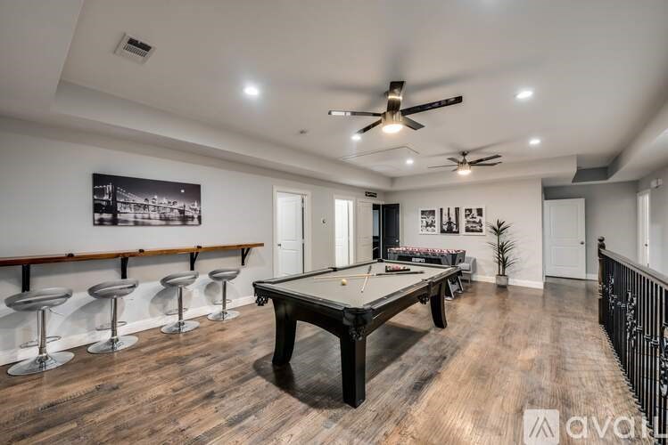A room with a pool table and bar stools.