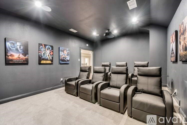 A row of leather recliner chairs are lined up in a room with posters on the wall.