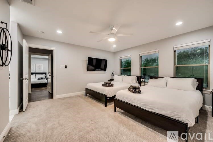 A bedroom with two beds and a television mounted on the wall.
