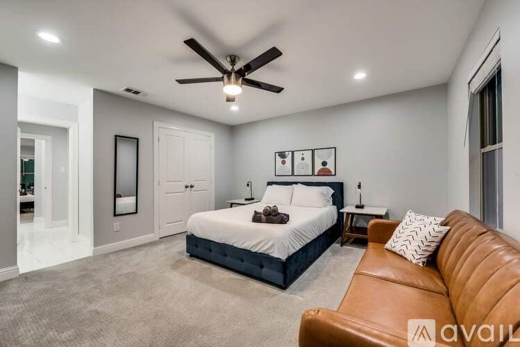 A bedroom with a bed, a couch, and a ceiling fan.