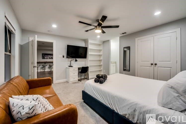A bedroom with a bed, a couch, and a ceiling fan.
