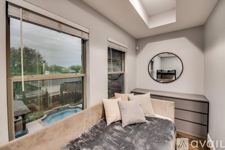 A bedroom with a large bed and a view of a pool through a window.