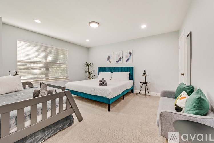 A bedroom with a bed, a couch, and a window with blinds.