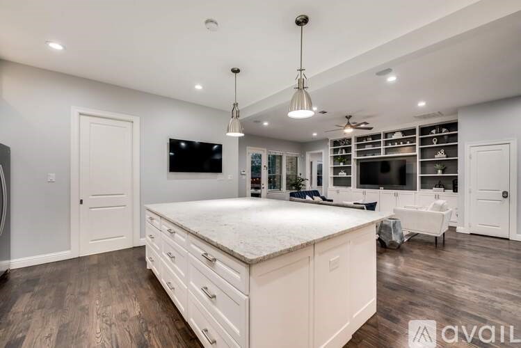 A spacious kitchen with a central island and a television mounted on the wall.