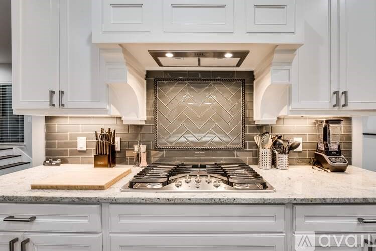 A modern kitchen with a stove top oven and white cabinets.
