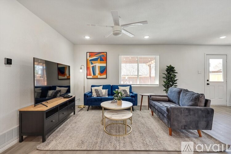 A living room with a blue couch, a white coffee table, and a television.