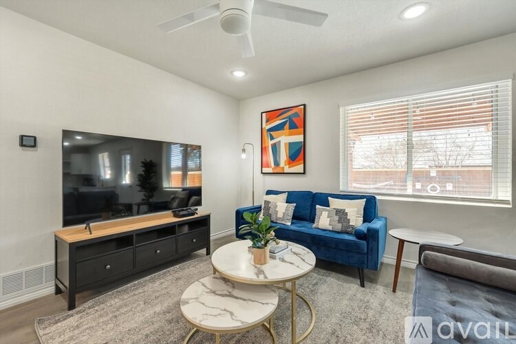 A living room with a blue couch, a television, and a painting on the wall.