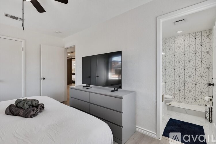 A bedroom with a bed, dresser, and television.