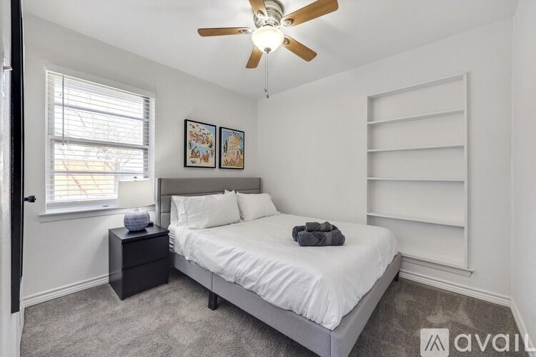 A bedroom with a bed, nightstand, and a ceiling fan.