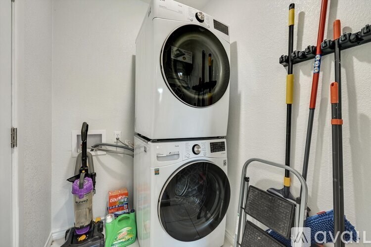 A white washing machine is stacked on top of a dryer in a small laundry room.
