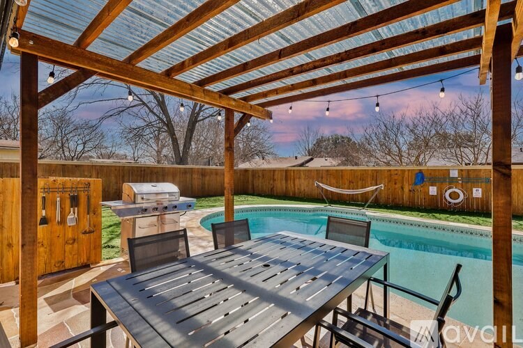 A wooden pergola over a table with a pool in the background.