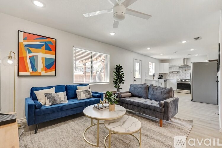 A living room with a blue couch and a painting on the wall.