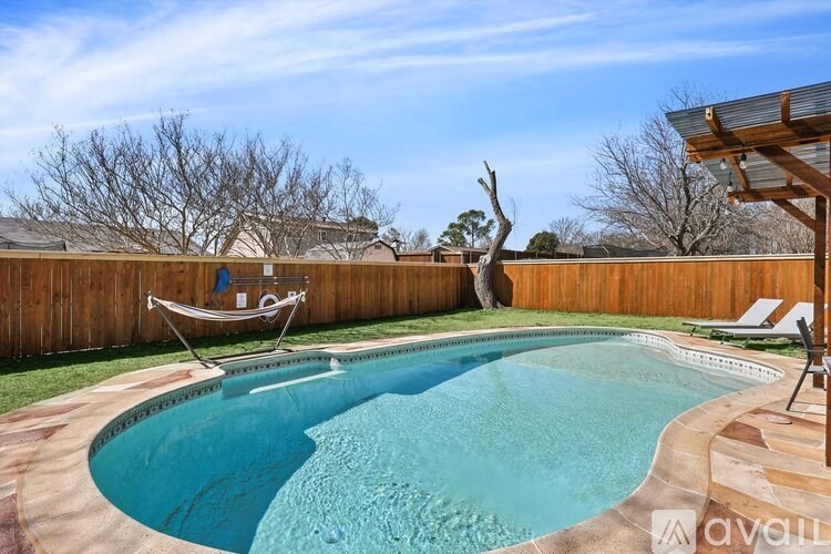 A small pool with a chair and a tree in the background.