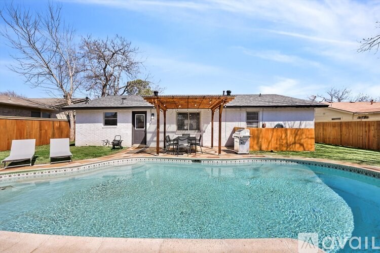 A pool in a backyard with a patio and a covered area.