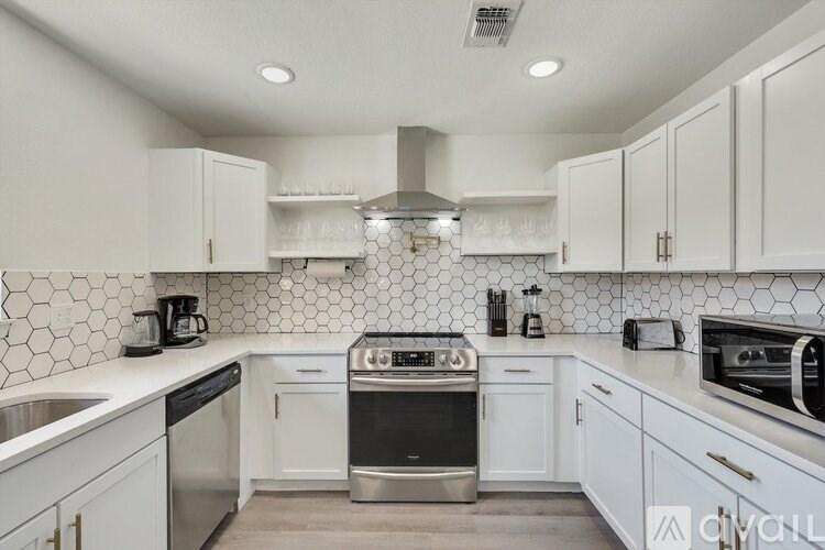 A modern kitchen with white cabinets and a black and white tiled backsplash.